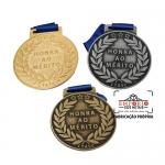 MEDALHA HONRA AO MERITO - Medalha com relevo, sem cor, banho de dourado, prata-velha e bronze, montada com fita de cetim azul.